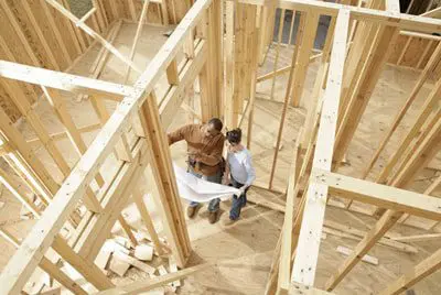 Two men are working on a house under construction.