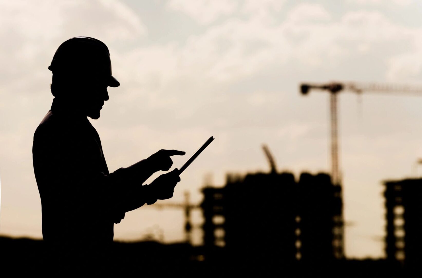 A man in a hard hat is holding a tablet.