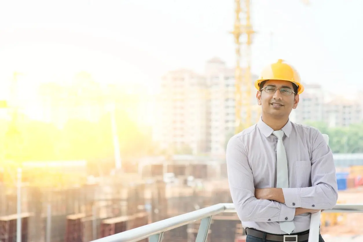 A man in a hard hat standing on top of a building.