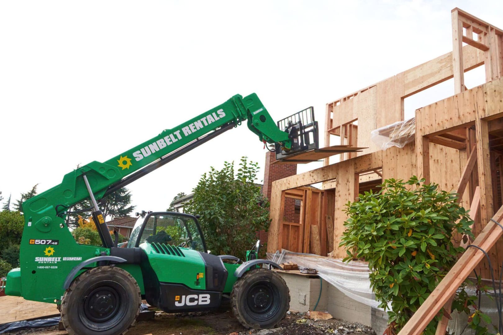 A green crane is in front of a building.