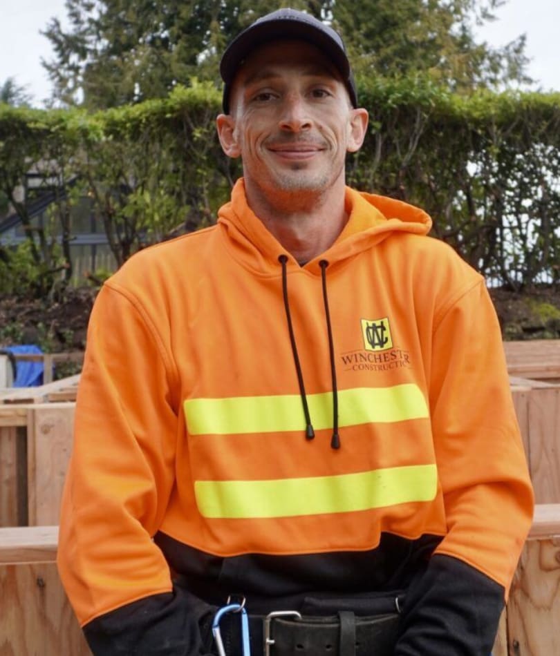 A man in an orange jacket and black hat.