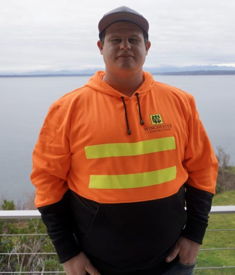 A man in an orange jacket standing on top of a hill.